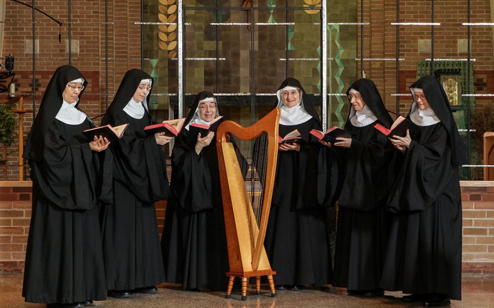 The Benedictine sisters of the Abbey of Sainte-Marie des Deux-Montagnes in Sainte-Marthe-sur-le-Lac, Quebec pose for a photo gathered around a harp in their community. (Courtesy of Serge Therrien)