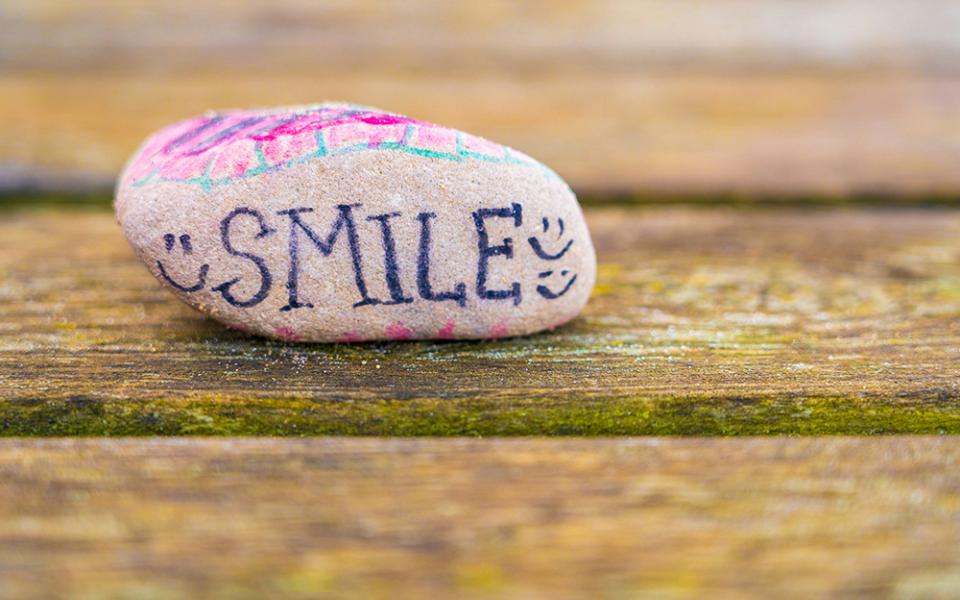 A rock with the word smile on it (Unsplash/Nick Fewings)