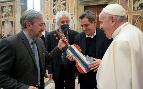 Pope Francis accepts a violin that prisoners in Milan made from the wood of a shipwrecked refugee boat during an audience with members of the Casa dello Spirito e delle Arti Foundation at the Vatican Feb. 4. (CNS/Vatican Media)