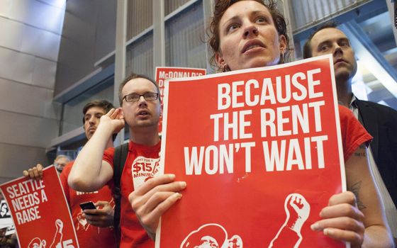 Labor activists hold signs during a Seattle City Council meeting in which the council voted on raising the minimum wage to $15 per hour, June 2, 2014, in Seattle. (CNS/David Ryder, Reuters)