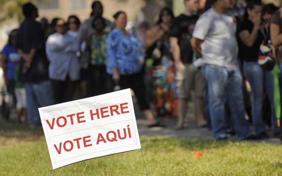 A sign in English and Spanish is seen as people wait to vote in 2012 outside a polling place in Kissimmee, Florida. (CNS/Reuters/Scott A. Miller)