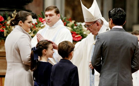 Pope Francis greets a family as they present offertory gifts during a Mass marking the feast of Mary, Mother of God, in St. Peter's Basilica at the Vatican Jan. 1, 2017. (CNS/Paul Haring)