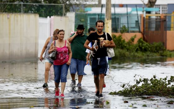 People walk in a flooded street Sept. 21 in Toa Baja, Puerto Rico, in the aftermath of Hurricane Maria. (CNS/EPA/Thais Llorca)