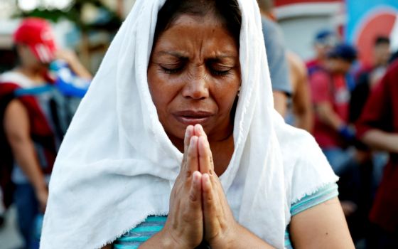 A migrant woman from El Salvador, part of a caravan traveling to the United States, prays during a stop Nov. 2, 2018, in Tecún Umán, Guatemala. (CNS/Reuters/Ueslei Marcelino)