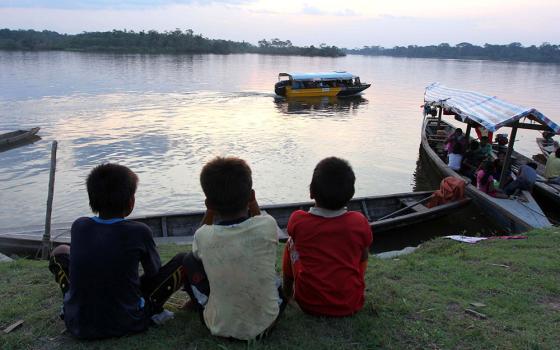 Kukama boys watch boats on the Amazon's Maranon River near Dos de Mayo in Peru's Loreto region. (CNS/Barbara Fraser)