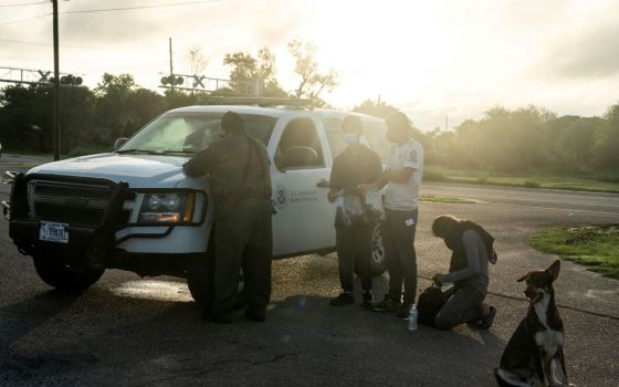 Migrants from Central America are processed July 8 by a Border Patrol agent in Penitas, Texas, after crossing the Rio Grande. (CNS photo/Go Nakamura, Reuters) 