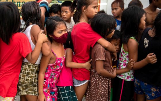 Children wait in line for free food from a relief program in a poor section of Manila, Philippines, Jan. 21. (CNS/Reuters/Eloisa Lopez)