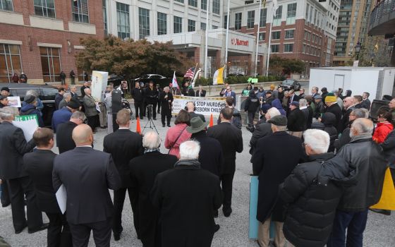 A clergyman leads a rosary with the National Men's March to End Abortion organizers Nov. 15, outside the hotel in Baltimore where the fall general assembly of the U.S. Conference of Catholic Bishops is being held Nov. 15-18. (CNS/Bob Roller)