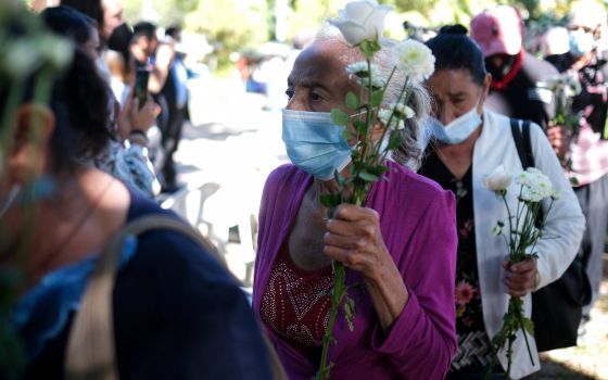 Women carry flowers as the arrive to take part in a ceremony to commemorate the 40th anniversary of the El Mozote massacre in El Salvador Dec. 11, 2021. (CNS photo/Jose Cabezas, Reuters)