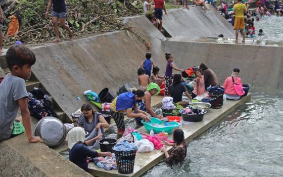 Residents clean their clothes near a river near Surigao City, Philippines, Dec. 18, 2021, in the aftermath of Typhoon Rai. The storm has claimed more than 370 lives. (CNS photo/Philippine Coast Guard handout via Reuters)