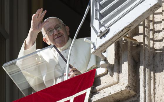 Pope Francis waves from the window of the papal apartment