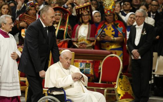 Pope Francis wheels by mass attendees in traditional attire