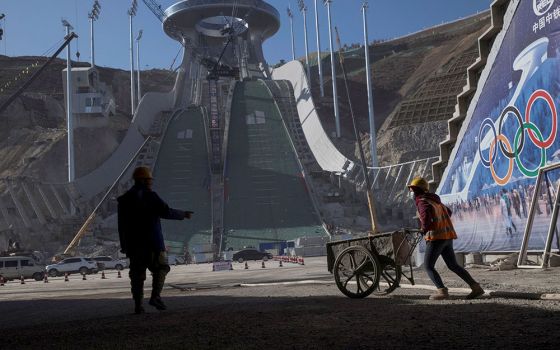 Workers are silhouetted Oct. 29, 2020, at the Thaiwoo ski resort near skiing venues of the 2022 Winter Olympics in Chongli, a popular ski resort town in China. The venue is one of many in the Beijing area that will host the Olympic Winter Games Feb. 4-20.