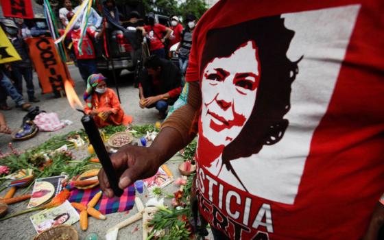 A demonstrator holds a candle as he protests outside the Supreme Court in Tegucigalpa, Honduras, June 20, 2022, during sentencing for Roberto David Castillo, former business executive and army intelligence officer. (CNS/Reuters/Fredy Rodriguez)