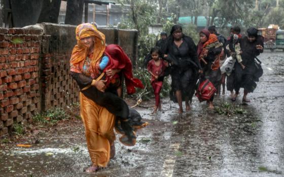 People walk through a downpour on flooded roads