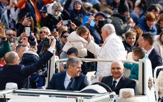 Pope Francis greets child during general audience. 