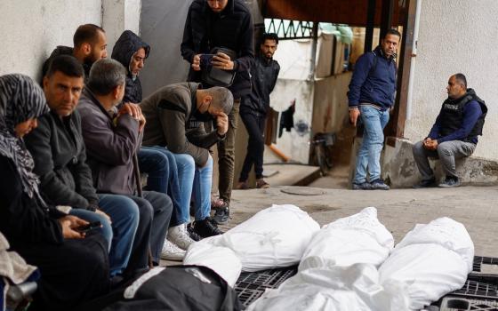 Palestinian mourn with shrouded bodies in foreground.