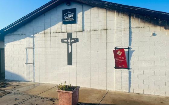 Front of small, one-story church building pictured with fire damage near blackened roof