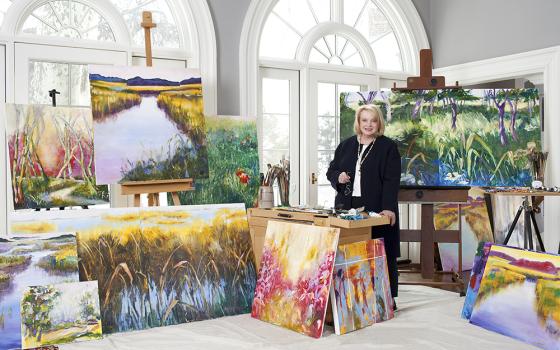 Janet Hennessey Dilenschneider poses with some of her paintings. The artist currently has an exhibit at the gallery of the Sheen Center for Thought and Culture in Manhattan, entitled "Come to the Light."