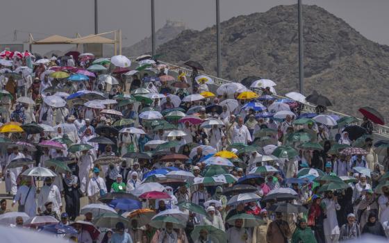 Large crowd pictured under their umbrellas against mountainous, desert terrain. 