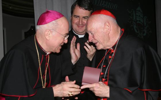 Archbishop Carlo Maria Vigano, then nuncio to the United States, congratulates then-Cardinal Theodore McCarrick of Washington at a gala dinner sponsored by the Pontifical Missions Societies in New York in May 2012. The archbishop has since said Cardinal McCarrick already was under sanctions at that time, including being banned from traveling and giving lectures. Oblate Fr. Andrew Small, center, director of the societies, said Vigano never tried to dissuade him from honoring the cardinal at the gala. (CNS/PM