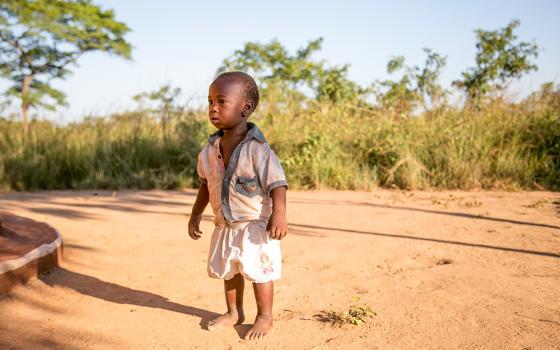 A Zambian child stands outside his home in the village of Ndombi. Crippling drought in Zambia has devastated agricultural production and caused extensive crop failure, leading to a food crisis that is mirrored across Africa and elsewhere in the tropics. (CNS/CRS/Michael Stulman)