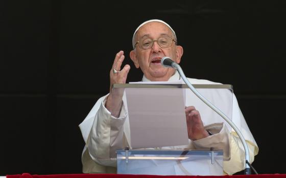 Pope Francis speaks from lectern, right hand raised in expression