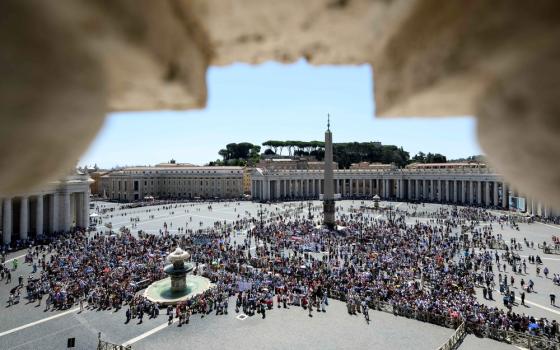 Crowd in square framed by stone outlook. 