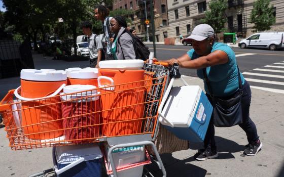 Woman pushes shopping cart filled with large coolers. 