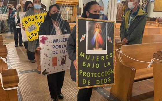Members of women's support circles gather at Most Holy Trinity Parish in Detroit, Michigan, to celebrate Mass on World Day of Migrants and Refugees in September 2021. "Women under God's protection" reads one sign in Spanish. 