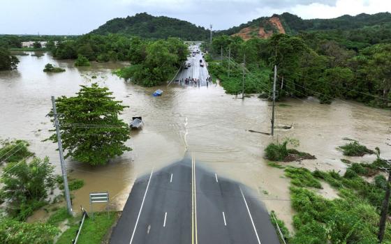 Aerial view of water completely covering middle of paved bridge. 