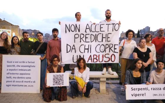 The ensemble poses, holding Italian-language signs. 