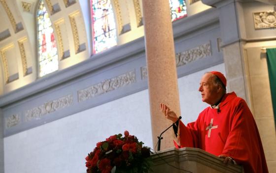 McElroy preaches from pulpit, the ceiling of the sanctuary fills the frame around him. 