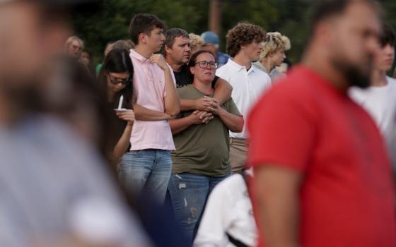 Pictured framed by out of focus people, center-focus on a small group of people holding each other.