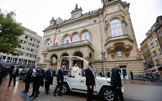 Pope Francis greets people gathered on the streets of Luxembourg to see him pass by in the popemobile Sept. 26, 2024. (CNS photo/Lola Gomez) 		