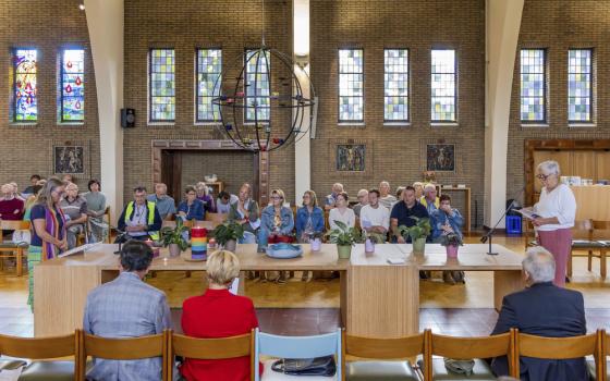 The two women stand at opposite ends of a long table, leading service.