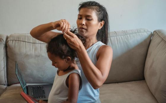 Woman prepares a girl's hair. 