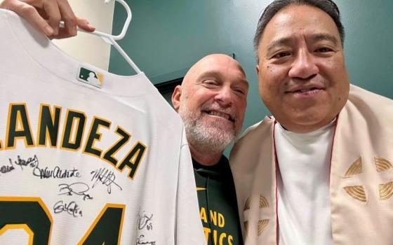 Fr. Jayson Landeza receives a personalized Oakland A's jersey, signed by the players, from the team's manager, Mark Kotsay.