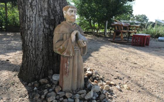 Statue against tree, ringed by stones. 