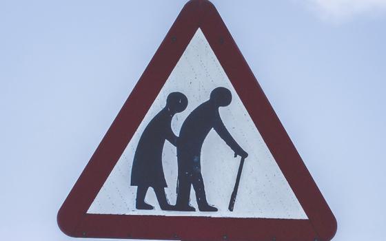 A crossing sign with two people, one with a cane (Unsplash/K Mitch Hodge)