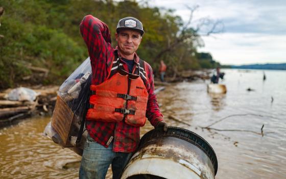 Pregracke stands by river holding debris item.