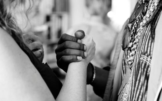 Two people clasping hands (Unsplash/Aaron Blanco)