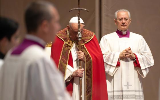 Francis, vested for mass, prays against crozier. 