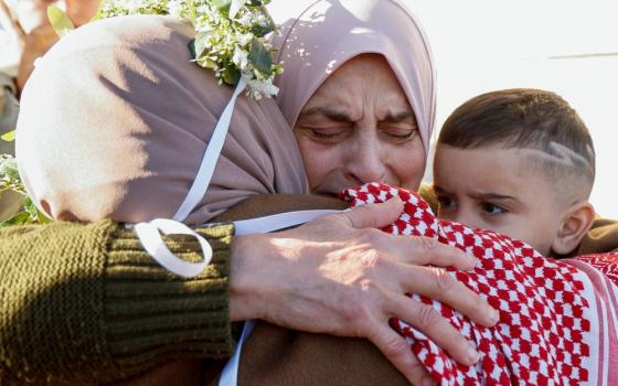 Woman's face crinkles with emotion as she embrace other woman and young boy.