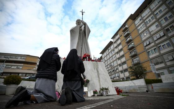 Nuns pray next to the statue of St. John Paul II outside Rome's Gemelli Hospital Feb. 20, 2025, where Pope Francis is admitted for treatment for a respiratory infection. The Vatican press office said early Feb. 20 that the pope had a peaceful night, "got up and had breakfast in an armchair." (OSV News photo/Guglielmo Mangiapane, Reuters)