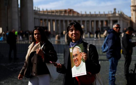  A woman smiles as she holds an image of Pope Francis in St. Peter's Square at the Vatican Feb. 26, 2025, as he continues his treatment for double pneumonia at Rome's Gemelli Hospital. The 88-year-old pontiff had a "restful night" and was sitting upright in an armchair, the Vatican said early Feb. 26. (OSV News photo/Claudia Greco, Reuters)