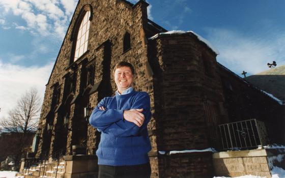 Fr. James Callan, then pastor of Corpus Christi Parish in Rochester, N.Y., poses in front of the church in 1997. (NCR file photo)