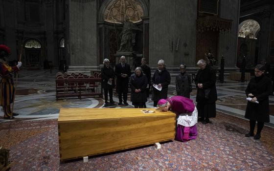 Archbishop Georg Gänswein, private secretary to Pope Benedict XVI, kisses the coffin of the late pope after his body was placed into it in St. Peter's Basilica at the Vatican on Jan. 4, 2023. (CNS/Vatican Media)