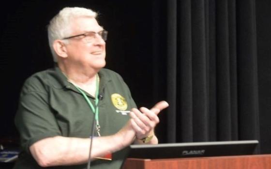 Holy Cross Fr. Stephen Newton, who serves as executive director of the Association of U.S. Catholic Priests, speaks at the podium during the AUSCP's 2022 annual assembly. (Courtesy of AUSCP)