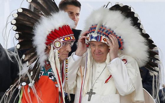 Pope Francis adjusts a traditional Indigenous headdress during a meeting with First Nations, Métis and Inuit communities at Maskwacis, Alberta, July 25. During a weeklong visit to Canada, the pope met with Indigenous groups.